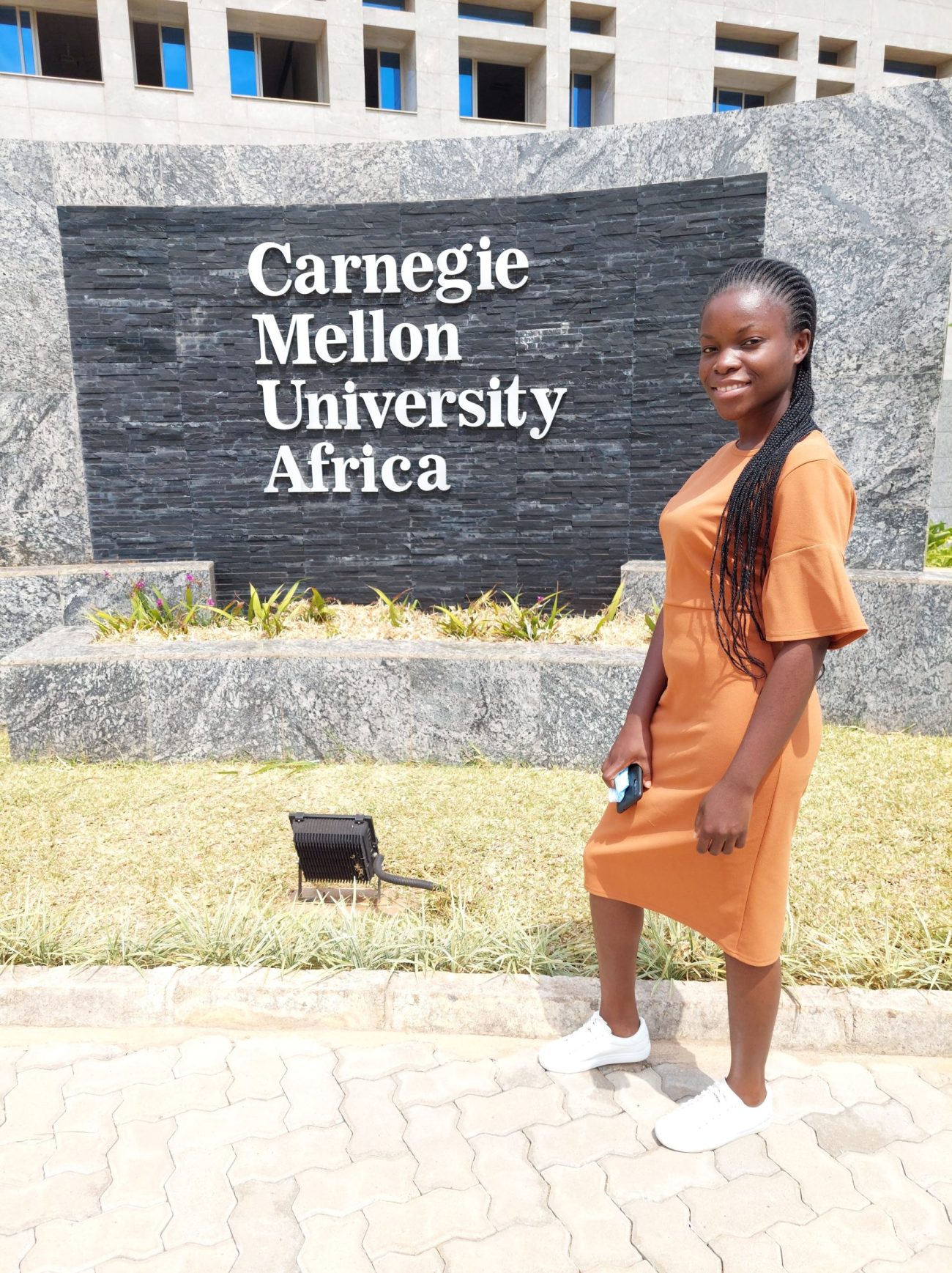 Furaha Benedict poses in front of CMU Africa sign