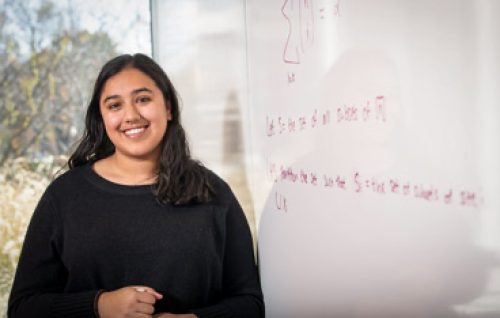 Harlene Samra stands in front of white board