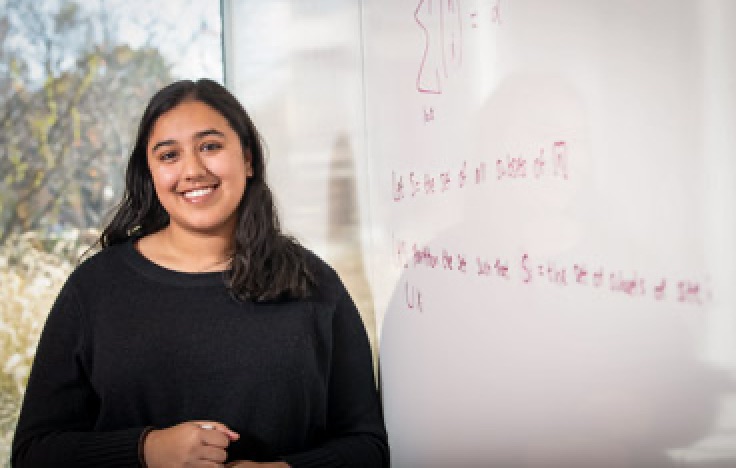 Harlene Samra stands in front of white board