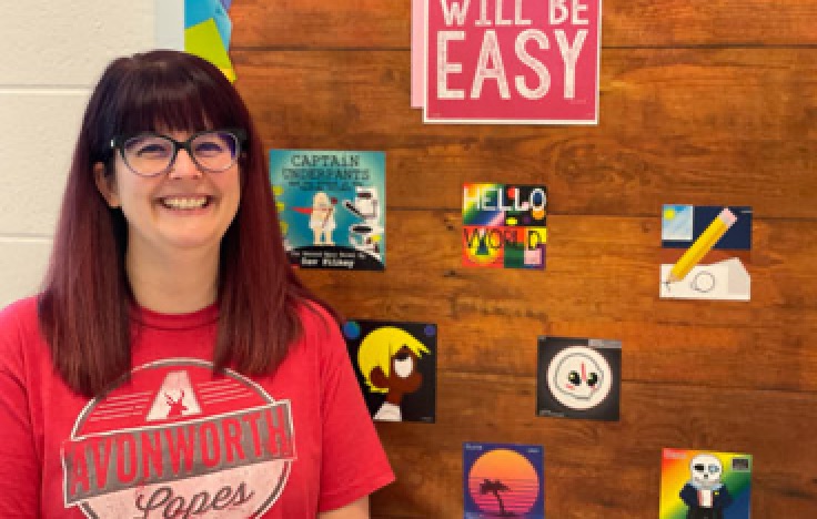 Jill Shumaker stands in front of wall displaying student work